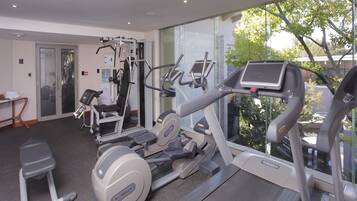 Un gimnasio moderno con máquinas de cardio, equipo de entrenamiento con pesas y una cinta de correr.