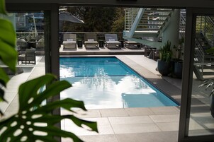 A modern outdoor pool area with lounge chairs and potted plants.