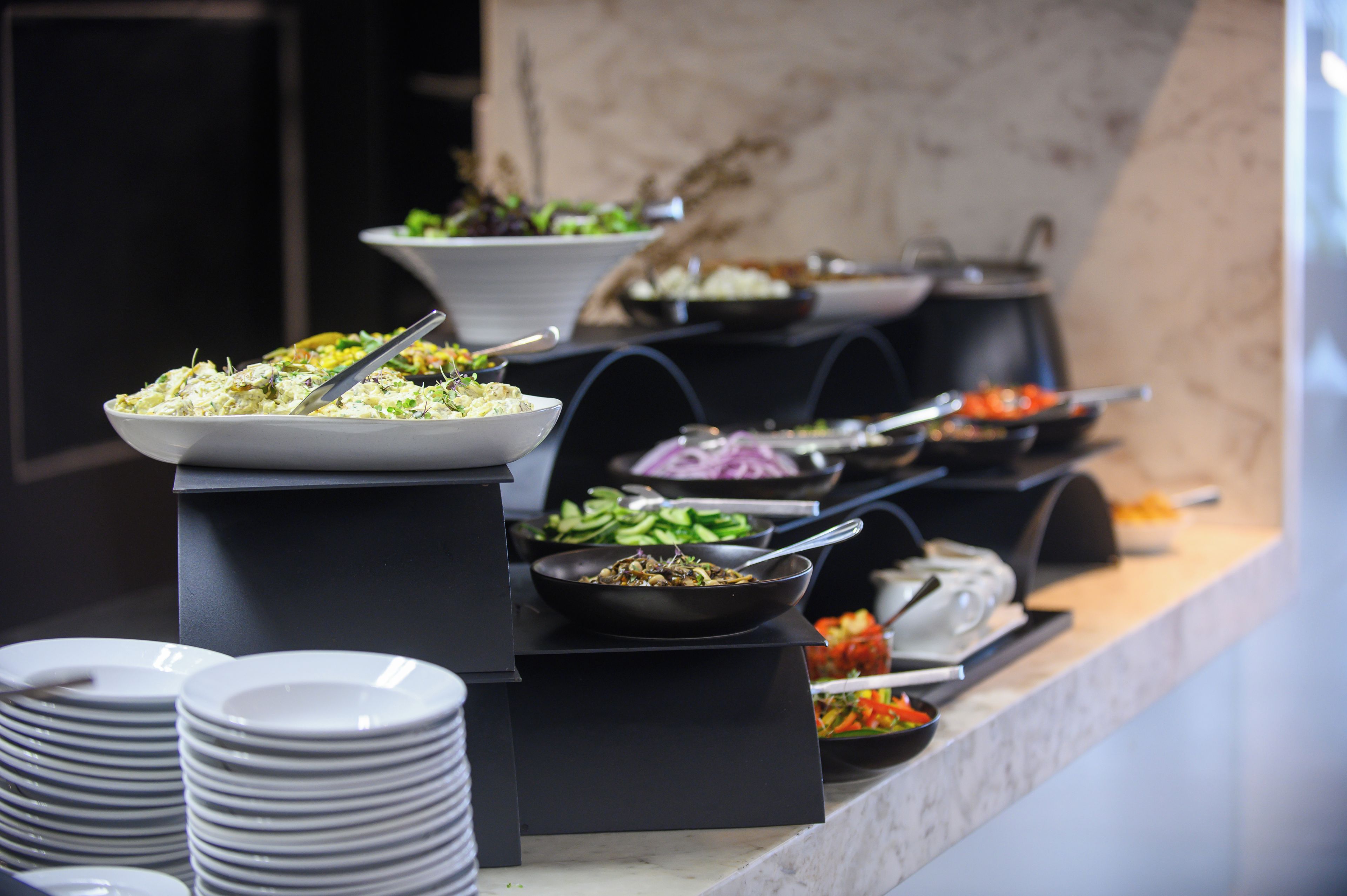 A buffet with various dishes and a stack of plates.