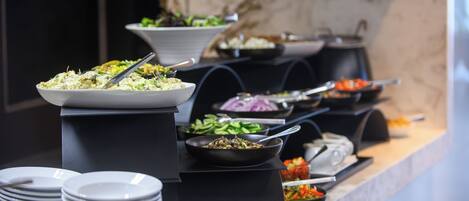 A buffet with various dishes and a stack of plates.