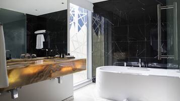 Un baño moderno con tocador de mármol, una bañera grande y un box de ducha de cristal.