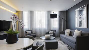 Una sala de estar moderna con un sofá, sillones, una mesa de centro y un televisor.