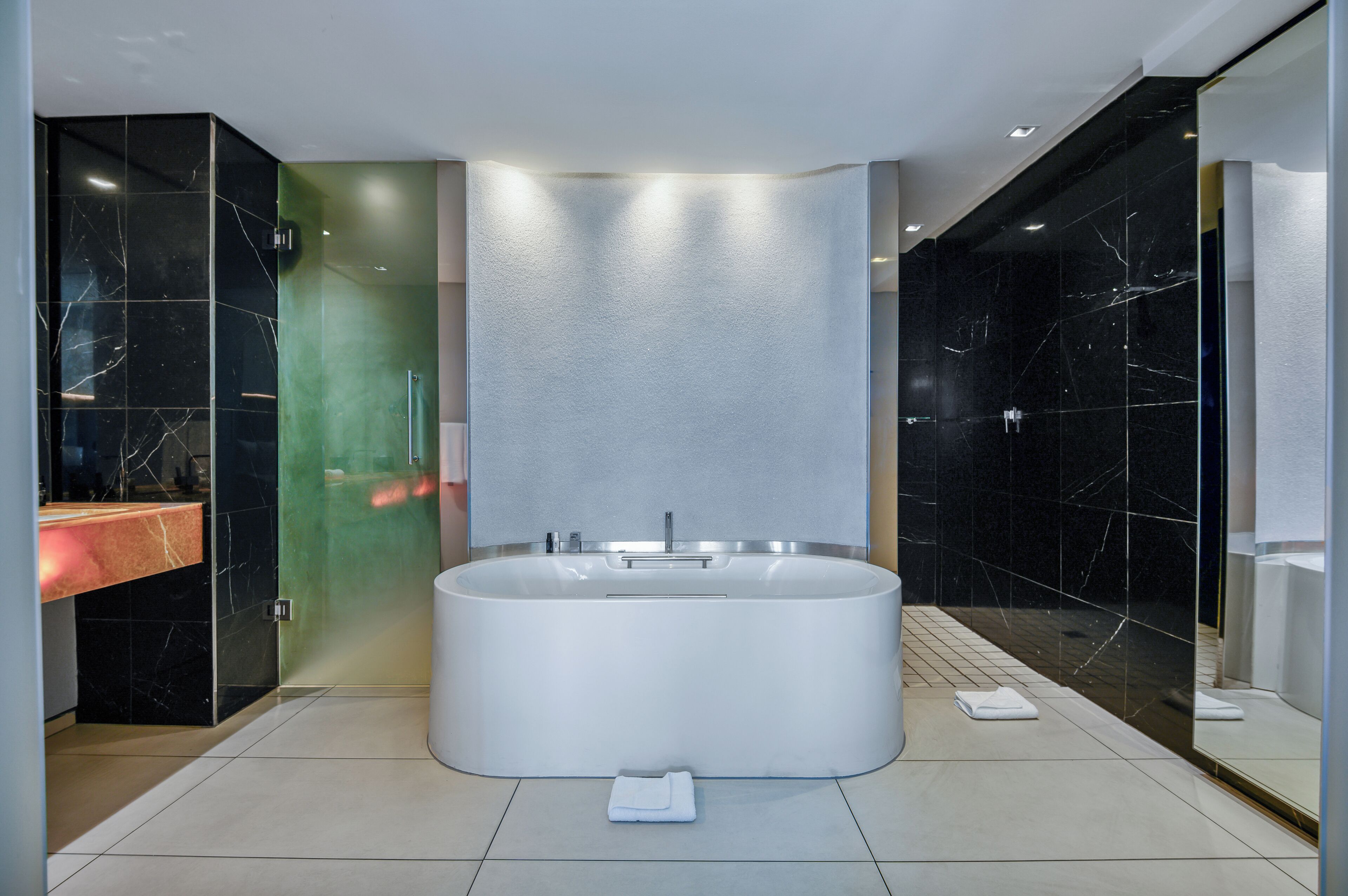 A modern bathroom with a large freestanding bathtub, a glass shower enclosure, and a marble-tiled floor.