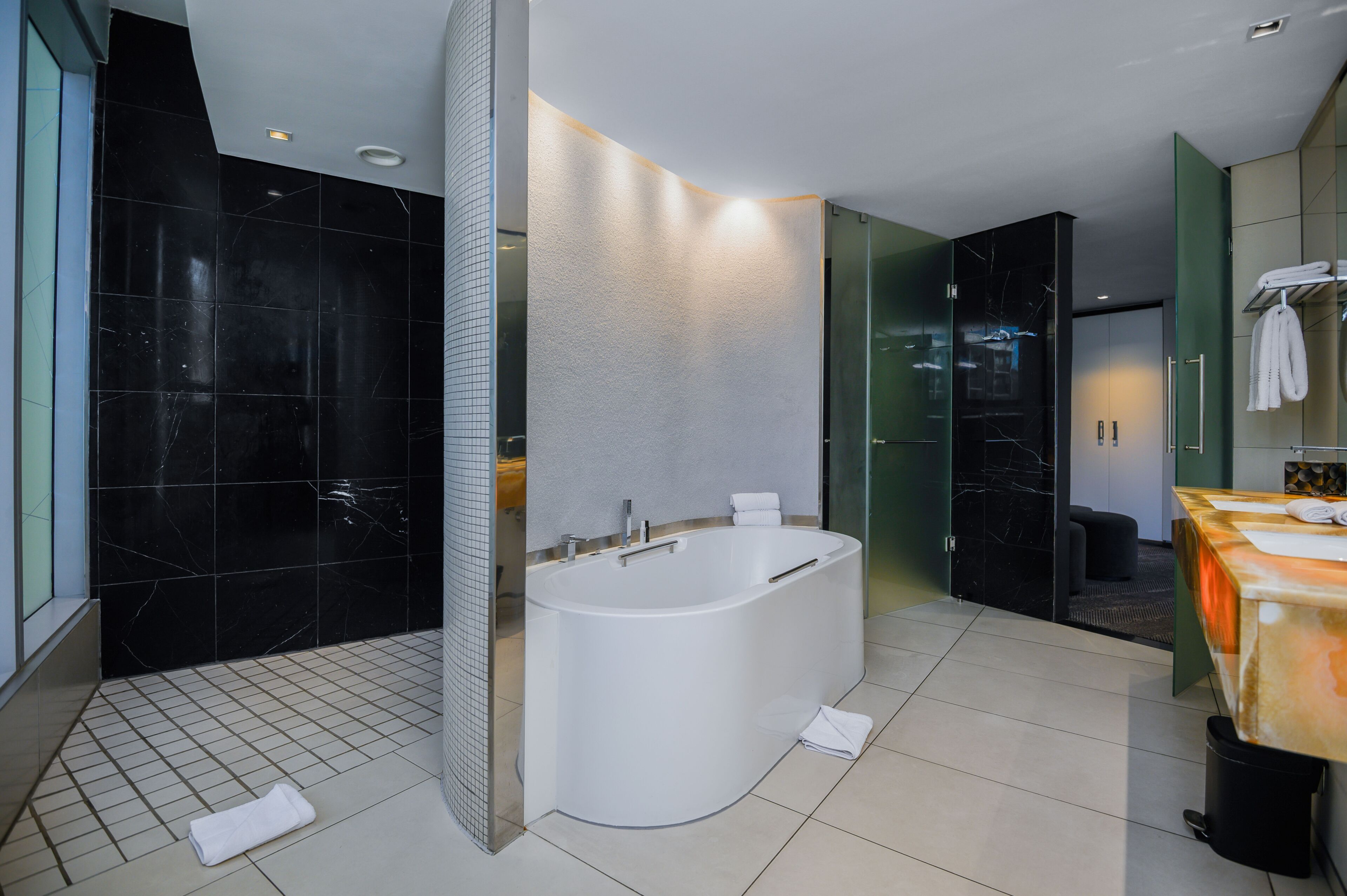 Ein modernes Badezimmer mit freistehender Badewanne, einer Duschkabine aus Glas und einem Waschtisch mit Handtuchhalter.