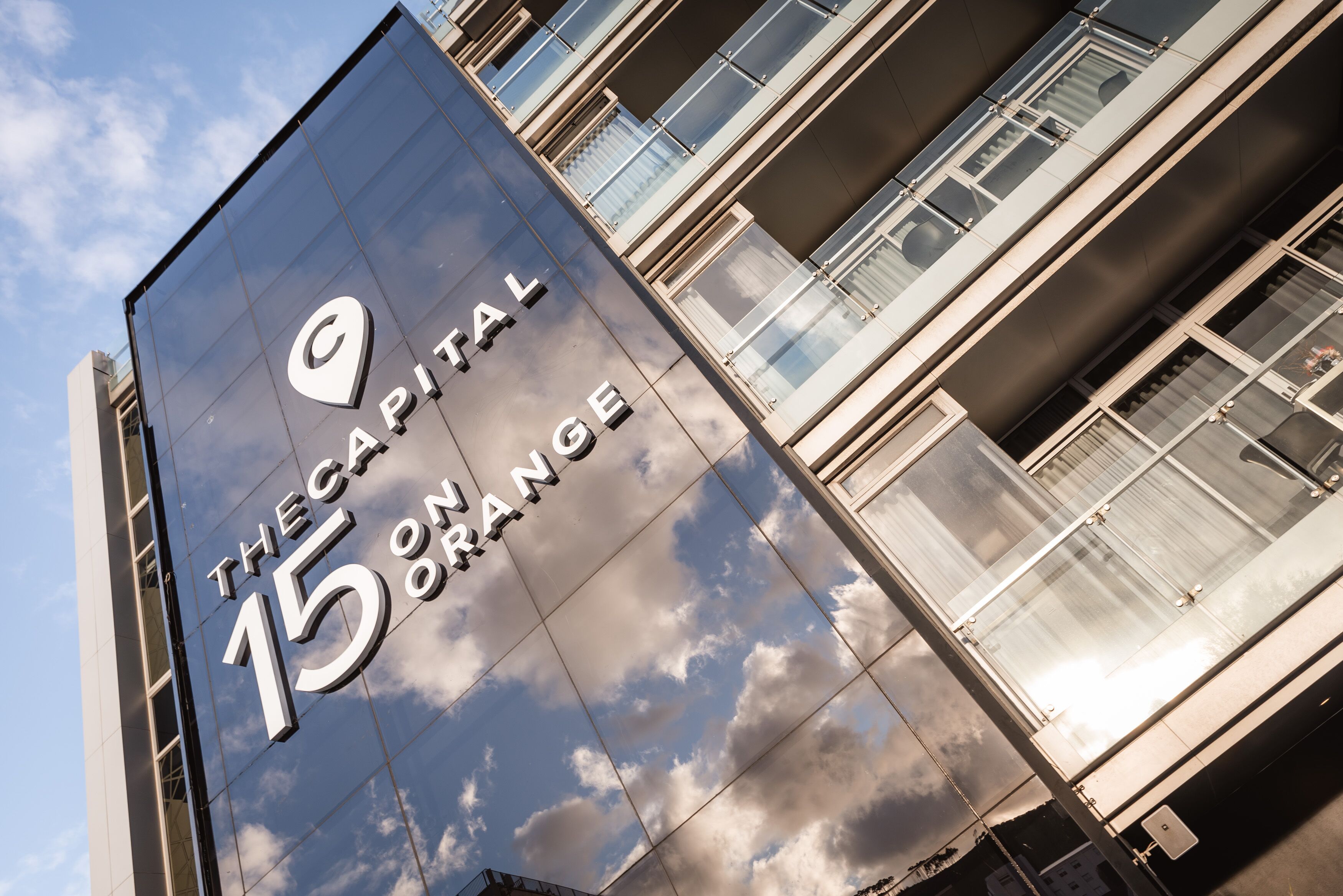 A building with a reflective glass facade displaying "THE CAPITAL 15 ON ORANGE" sign.