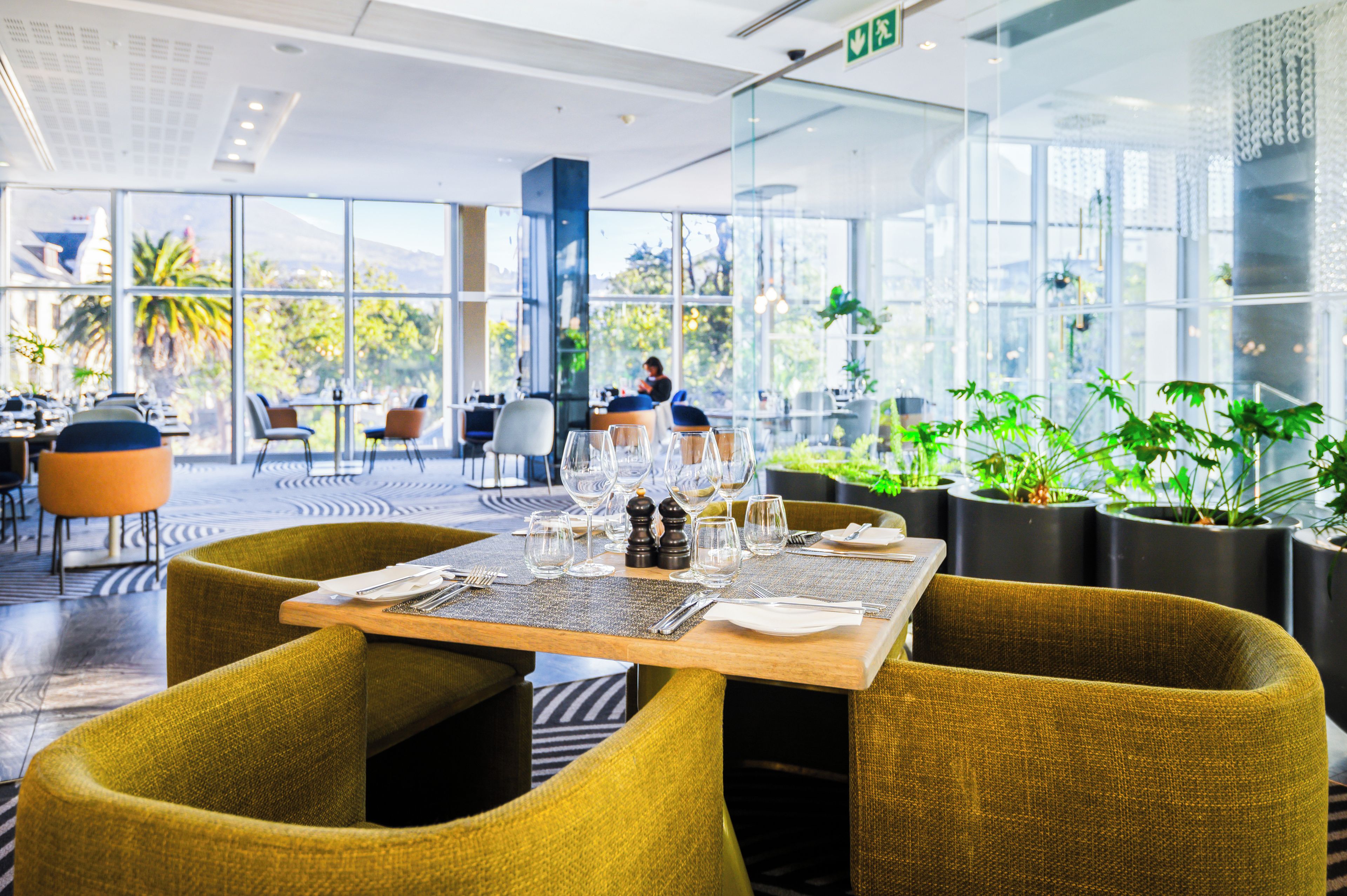Un restaurant avec une table dressée, des chaises et des plantes en pot.