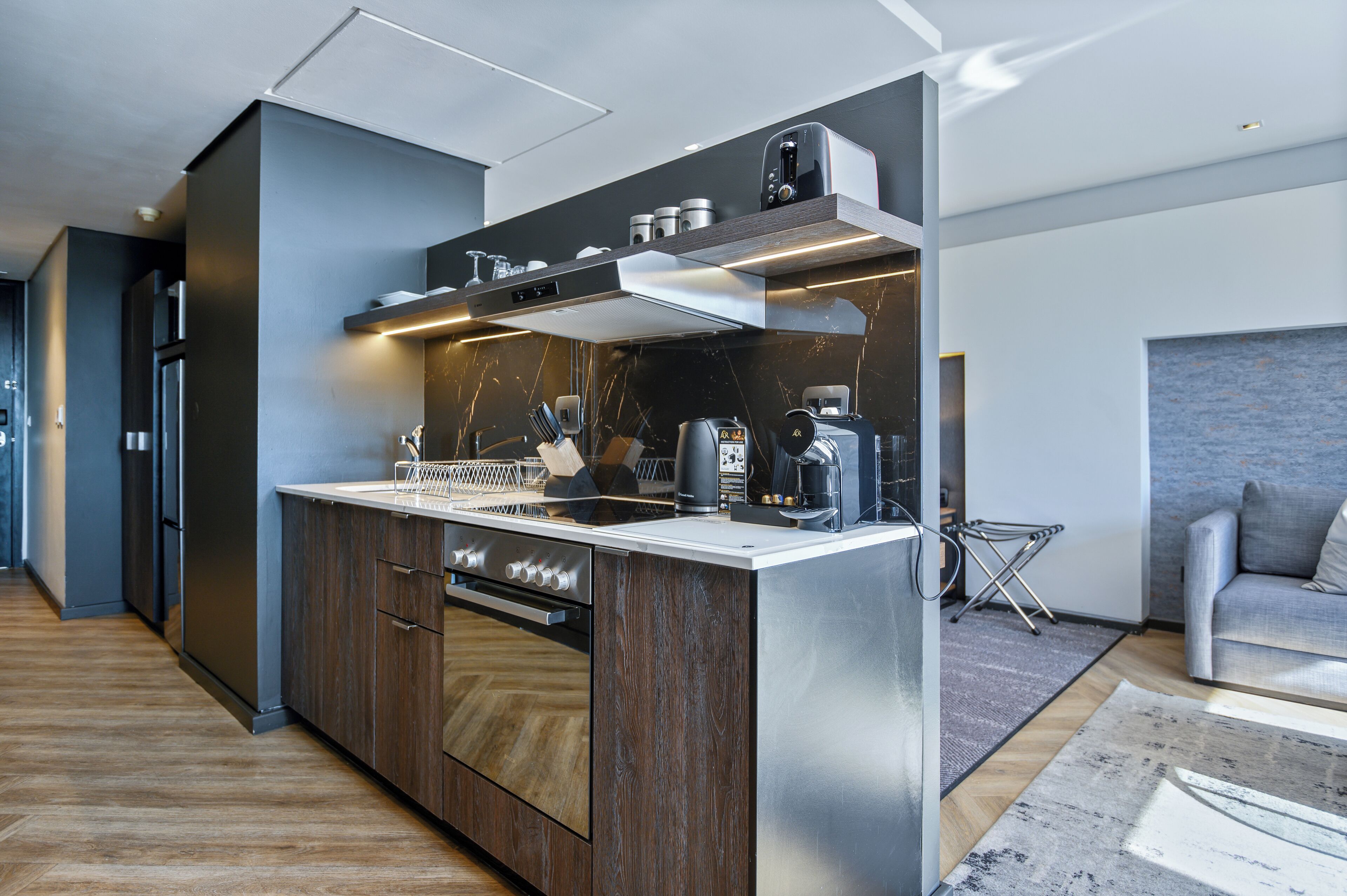 A modern kitchen with a central island, built-in oven, and stainless steel appliances.