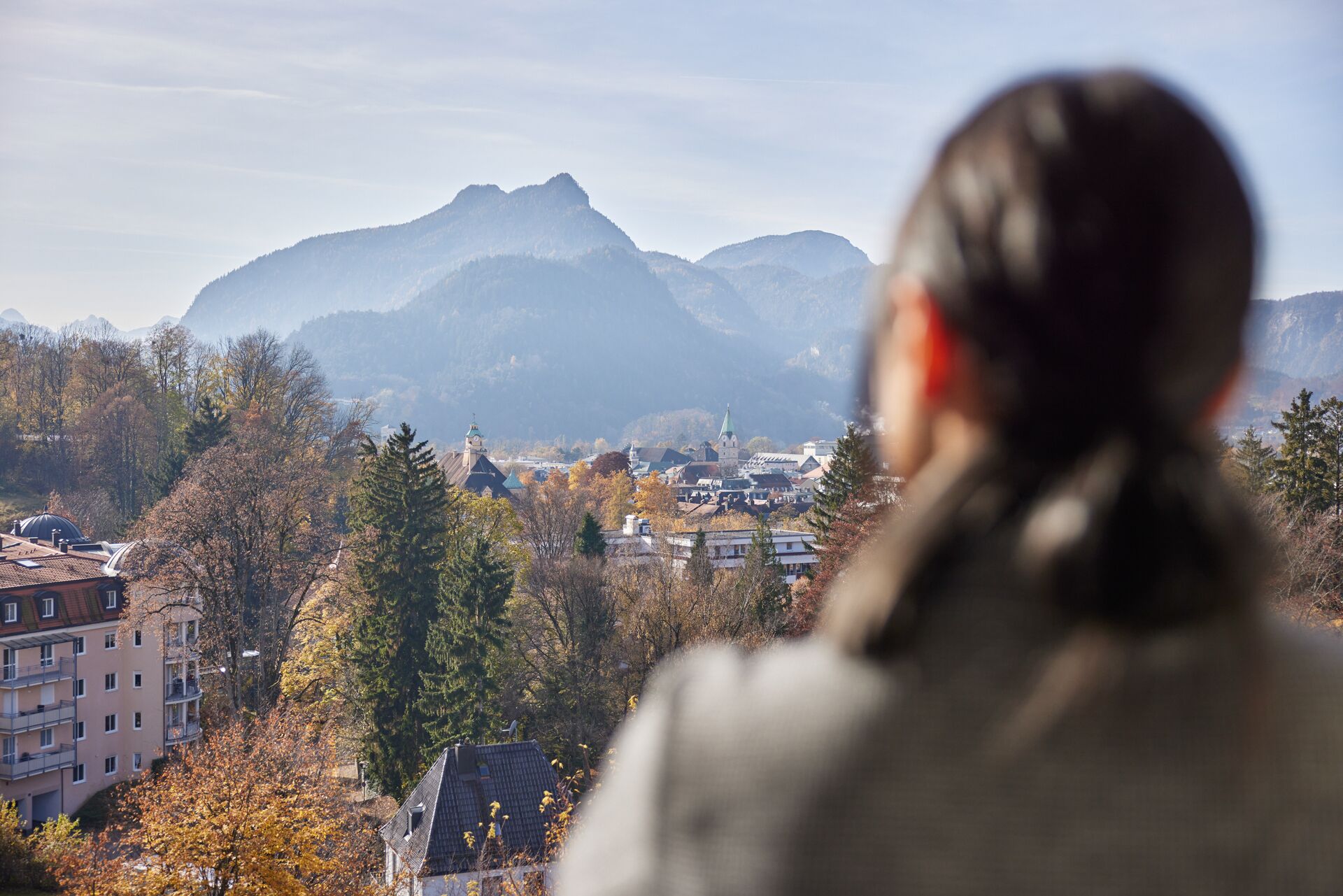 Una persona contemplando un pueblo con montañas al fondo.