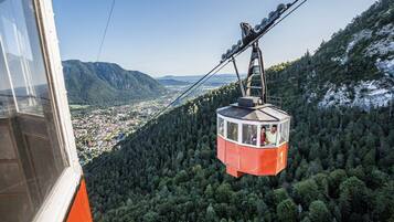 A cable car suspended over a forested mountain area.