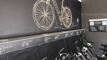 Een deelautofietspunt met meerdere fietsen en een bord dat aan de muur is bevestigd, waarop staat geschreven: 'RUNDUM eBIKE SHARING'.