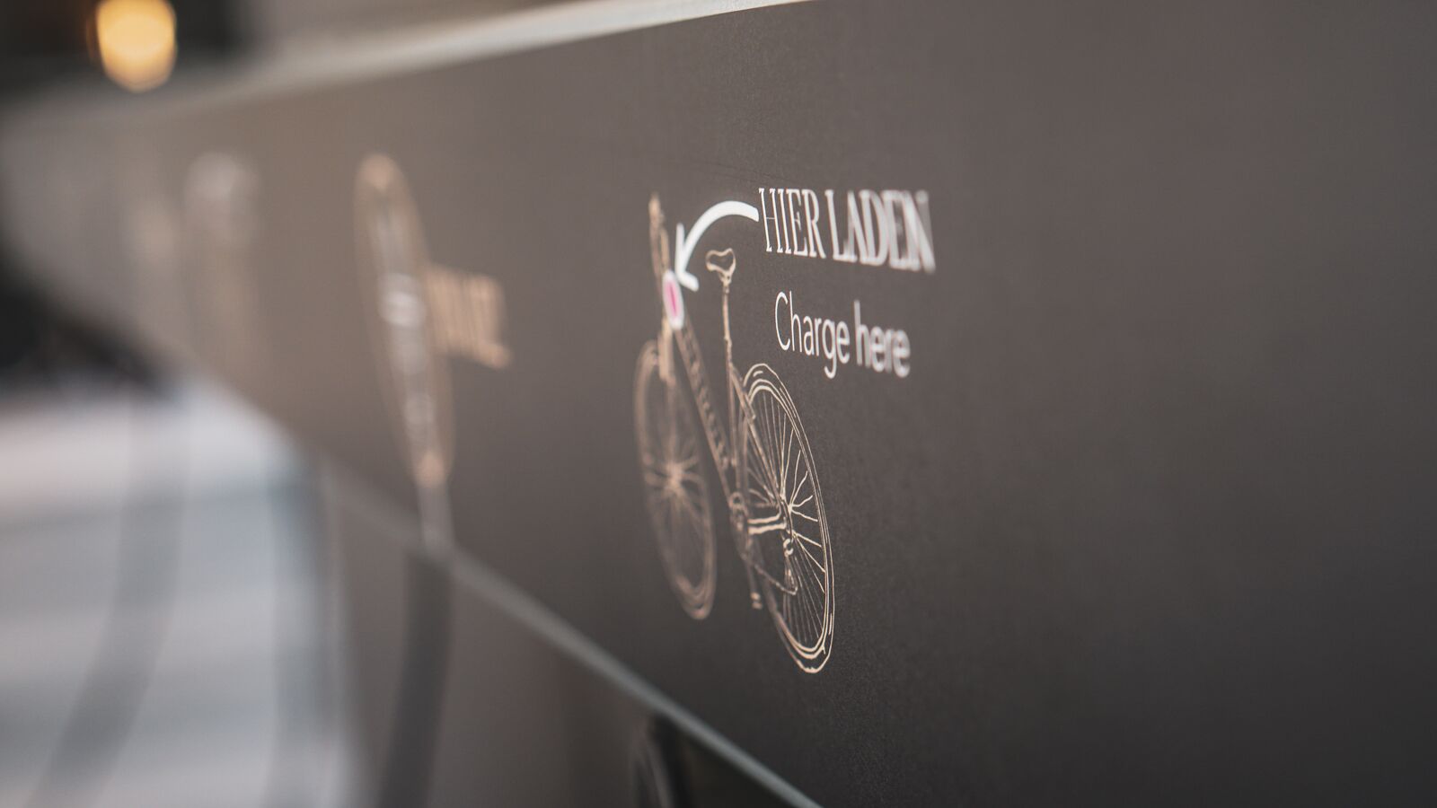 A wall with a bicycle and the text "HER LADEN Charge here".