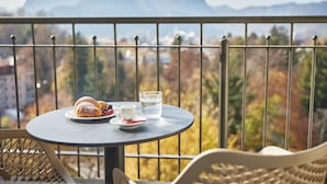 Un balcón con una mesa dispuesta para el desayuno, que incluye cruasanes, frutos rojos y un vaso de agua.
