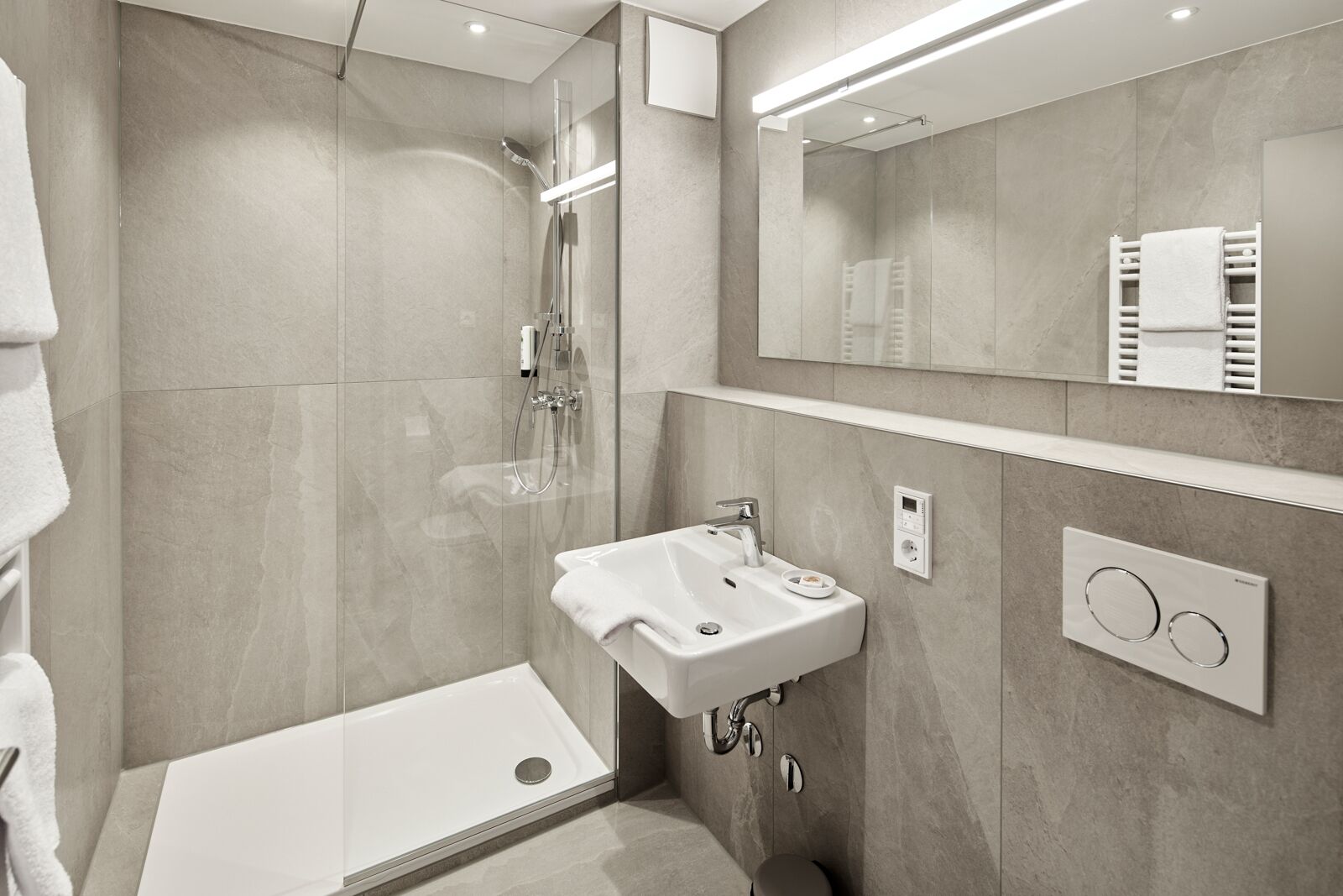 A modern bathroom with a glass-enclosed shower, a white sink, and a towel rack.