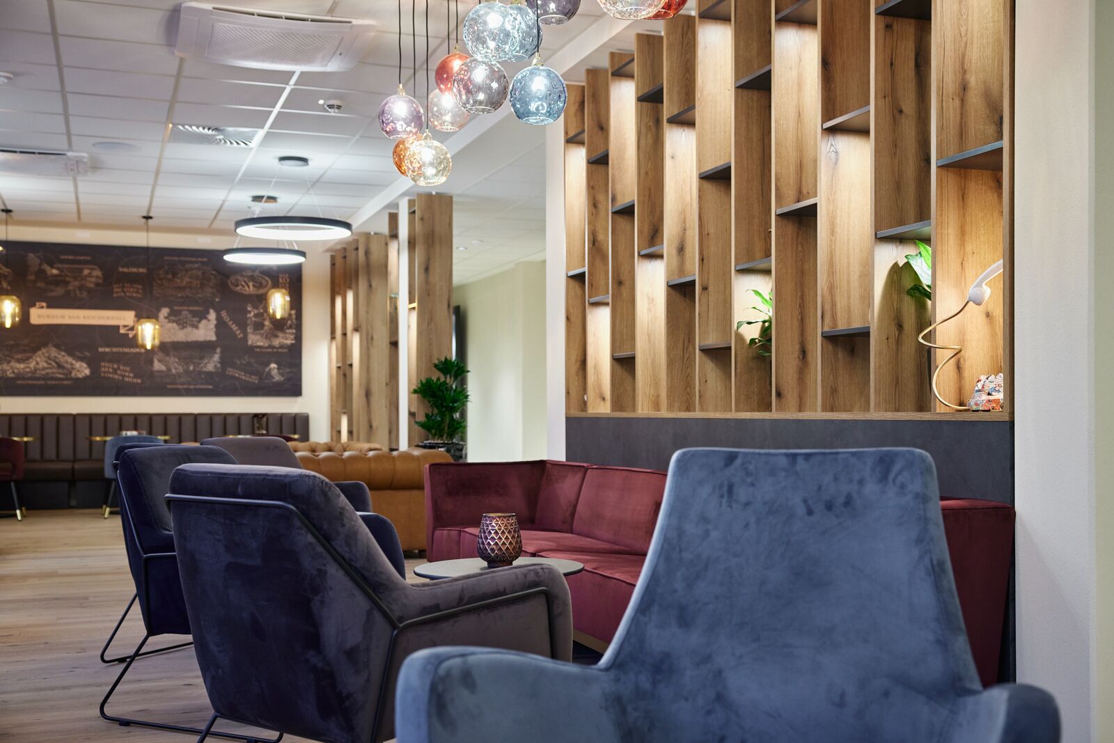 Un espace de détente moderne avec des fauteuils confortables, des étagères en bois et des luminaires décoratifs suspendus.