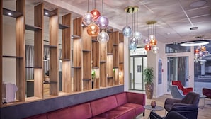 Un interior moderno con un sofá rojo, estanterías de madera y luces colgantes coloridas.