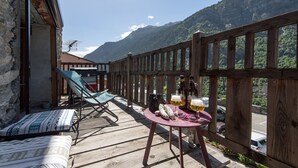 Una terraza de madera con una mesa preparada para dos personas, una silla y un sofá.