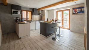 Una cocina moderna con una isla central, vigas de madera y un ventanal amplio.