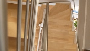 Un escalier avec une rampe métallique, des marches en bois et un mur blanc.