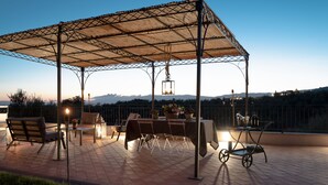 Une terrasse extérieure dotée d’un espace salon abrité, d’une table et de chaises.