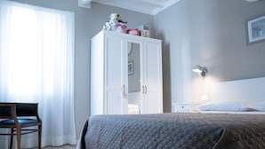 Une chambre à coucher avec un lit, une armoire, une chaise et une table de chevet.