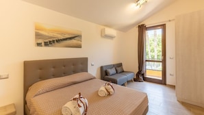 Ein Schlafzimmer mit einem großen Bett, einem Sofa, einer Klimaanlage und einem Fenster mit Vorhängen.