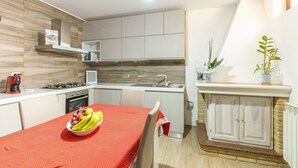 Eine moderne Küche mit weißen Schränken, einer roten Tischdecke und einer Obstschale.