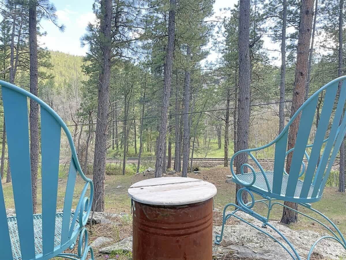 Deux chaises en métal bleu et une table ronde, le tout installé dans un cadre forestier.