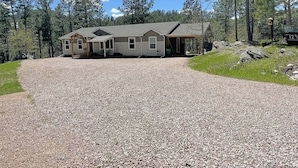 A two-story house with a gravel driveway leading to a covered porch.