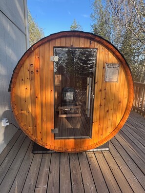 A sauna with a wooden exterior, a glass door, and a sign indicating sauna rules.