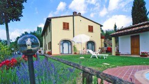 Une maison à deux étages avec un jardin, une piscine et une clôture en bois.
