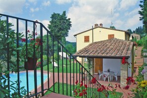 A house with a tiled roof, a swimming pool, and a garden with red flowers. - APARTMENT WITH WINDOWS VIEW ON THE POOL AND ON THE WONDERFUL TUSCAN COUNTRYSIDE  (Gambassi Terme)