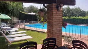 Ein Poolbereich mit Liegestühlen und einer Ziegelsteinsäule.