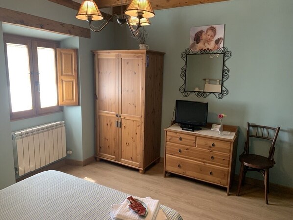 Un dormitorio con cama, armario de madera, cómoda, silla y televisor.