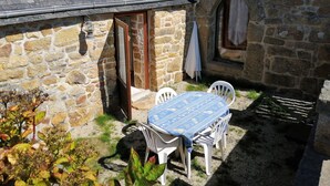 A stone building with a small patio area, a table with chairs, and a window.