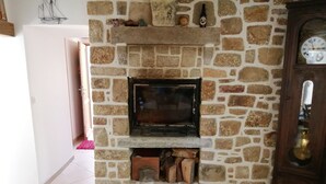 A stone fireplace with a television, a clock, and a bottle on the mantel.