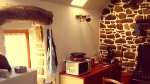 A kitchen with a stone wall, a dining table with chairs, a microwave, and a stove.