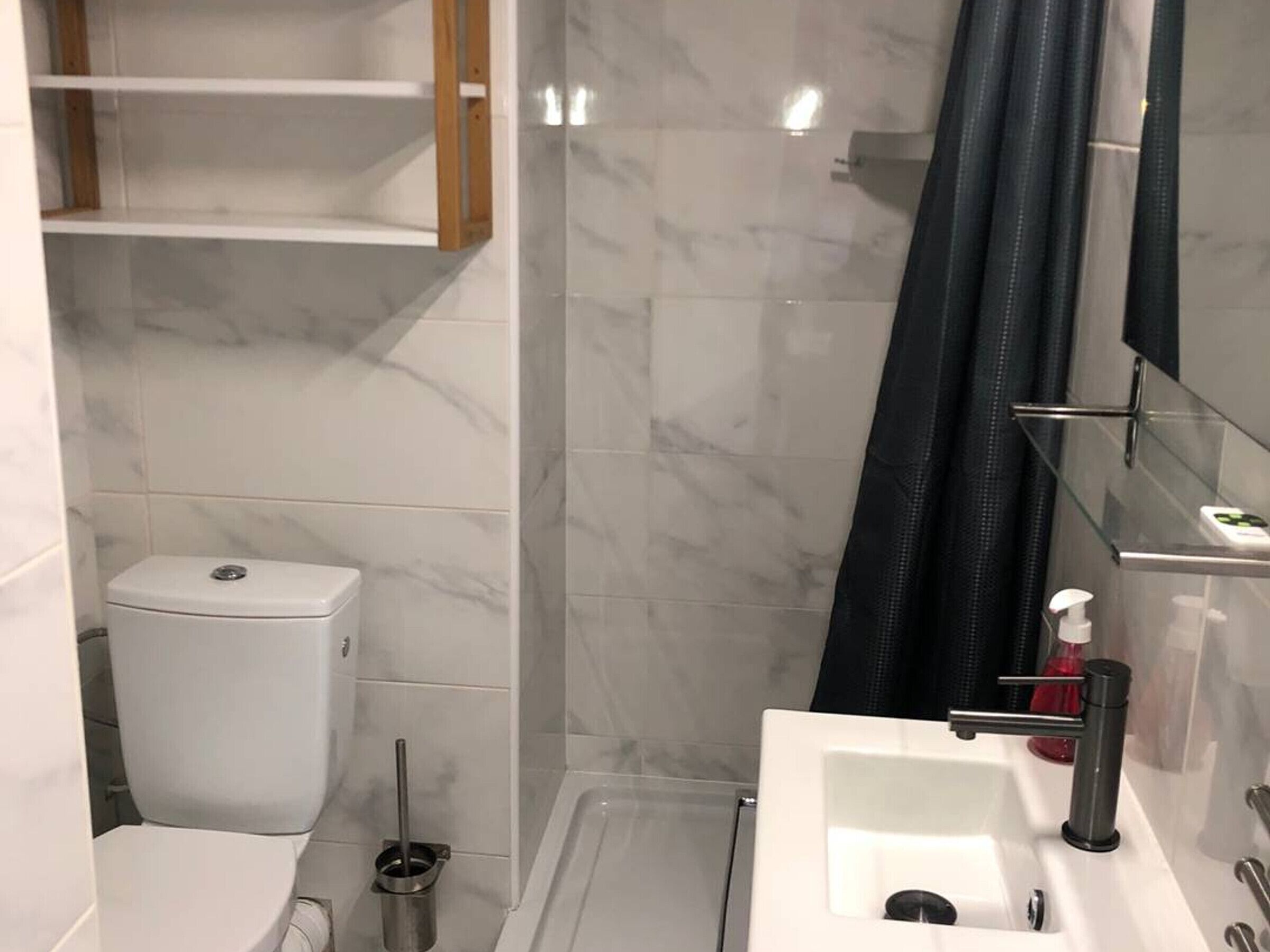 Et moderne badeværelse med toilet, håndvask og bruseområde.