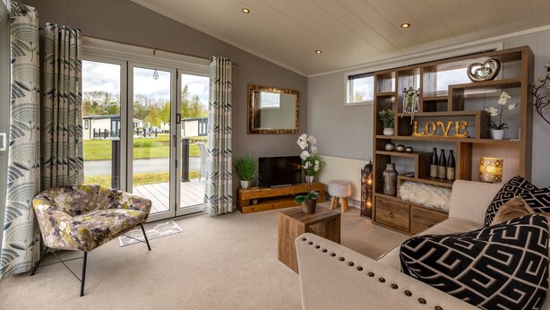 A spacious living room with a large sliding glass door, a comfortable sofa, a wooden coffee table, and a TV stand. - Inside No. 1 Retreat (Carnforth)
