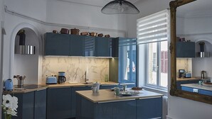 Una cocina moderna con armarios azul oscuro, un salpicadero de mármol y un amplio ventanal.