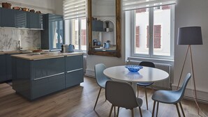 Una cocina moderna con una isla central, un comedor con mesa redonda y un espejo grande.