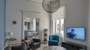 Una sala de estar moderna con un sofá, sillones, una mesa de centro y un televisor que muestra a un hombre en un barco.