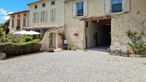 Un bâtiment doté d’une cour en gravier, d’un patio couvert et d’un petit jardin agrémenté de plantes en pot.