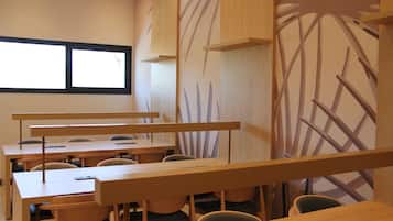 A classroom with wooden desks and chairs, a large window, and a wall with a plant design.