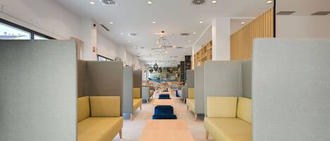A modern interior with seating areas, tables, and a kitchen in the background.