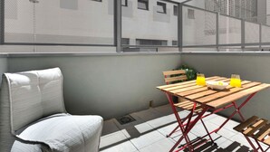 Un balcón con mesa, sillas y vistas a un edificio con múltiples ventanas.