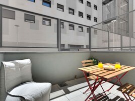 Un balcón con mesa, sillas y vistas a un edificio con múltiples ventanas.