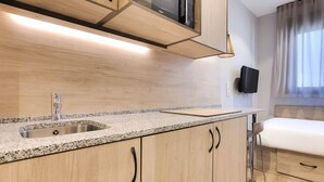 Una cocina moderna con encimeras de granito, pileta de acero inoxidable, armarios de madera y microondas integrado.