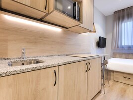 Una cocina moderna con encimeras de granito, pileta de acero inoxidable, armarios de madera y microondas integrado.