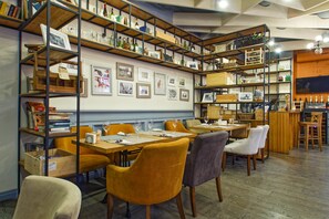 A restaurant with high wooden bookshelves, framed pictures on the walls, and a bar area. - Minima Krasnye vorota (Moscow)
