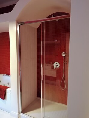 A glass-enclosed shower area with a red-tiled wall and a white bathtub with a red towel. - Cà del Mago, luxury, private heated pool and spa a stone's throw from the sea (Lerici)